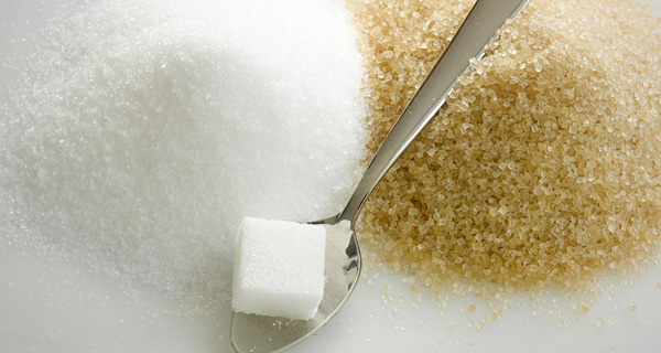 A spoon with sugar cubes and brown sugar on it.