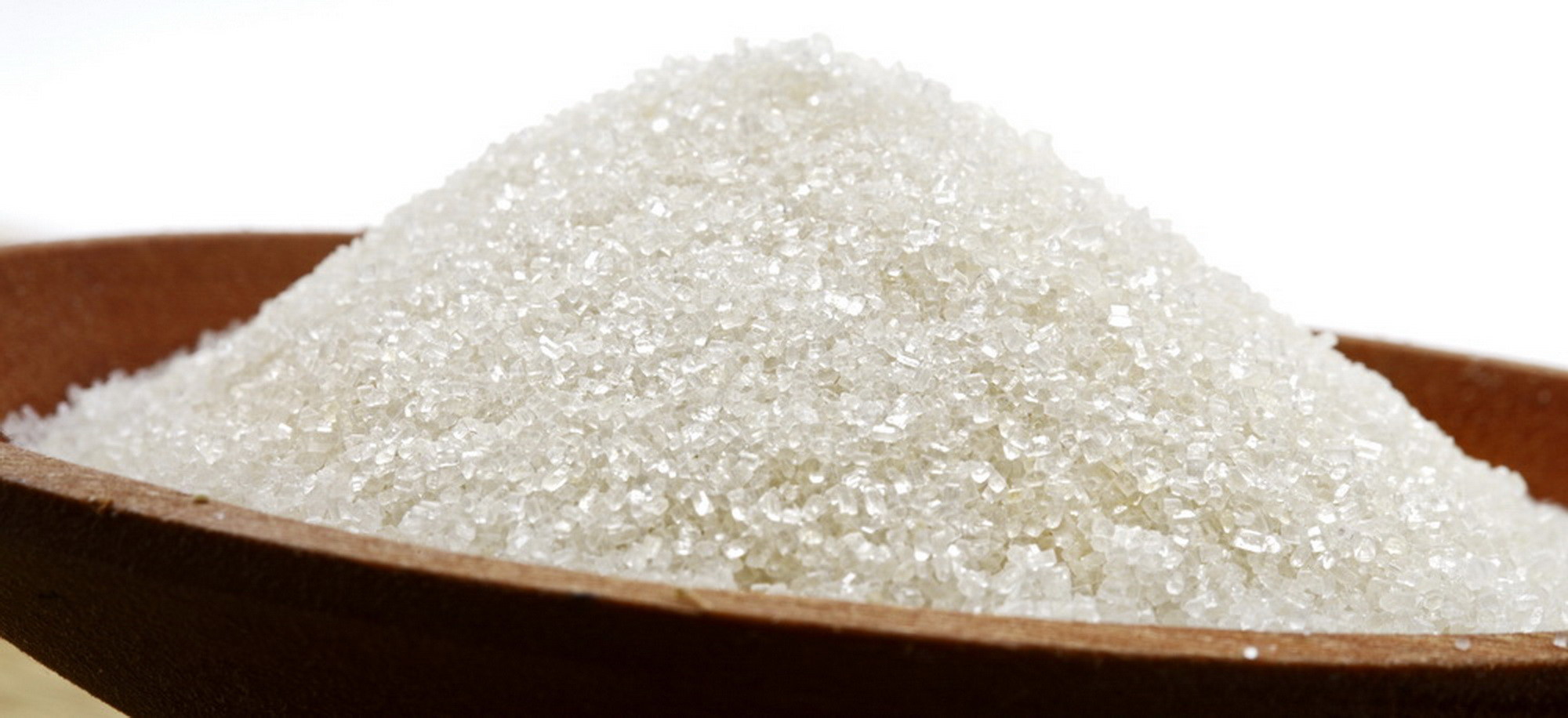 A close up of white sugar on top of a wooden table.