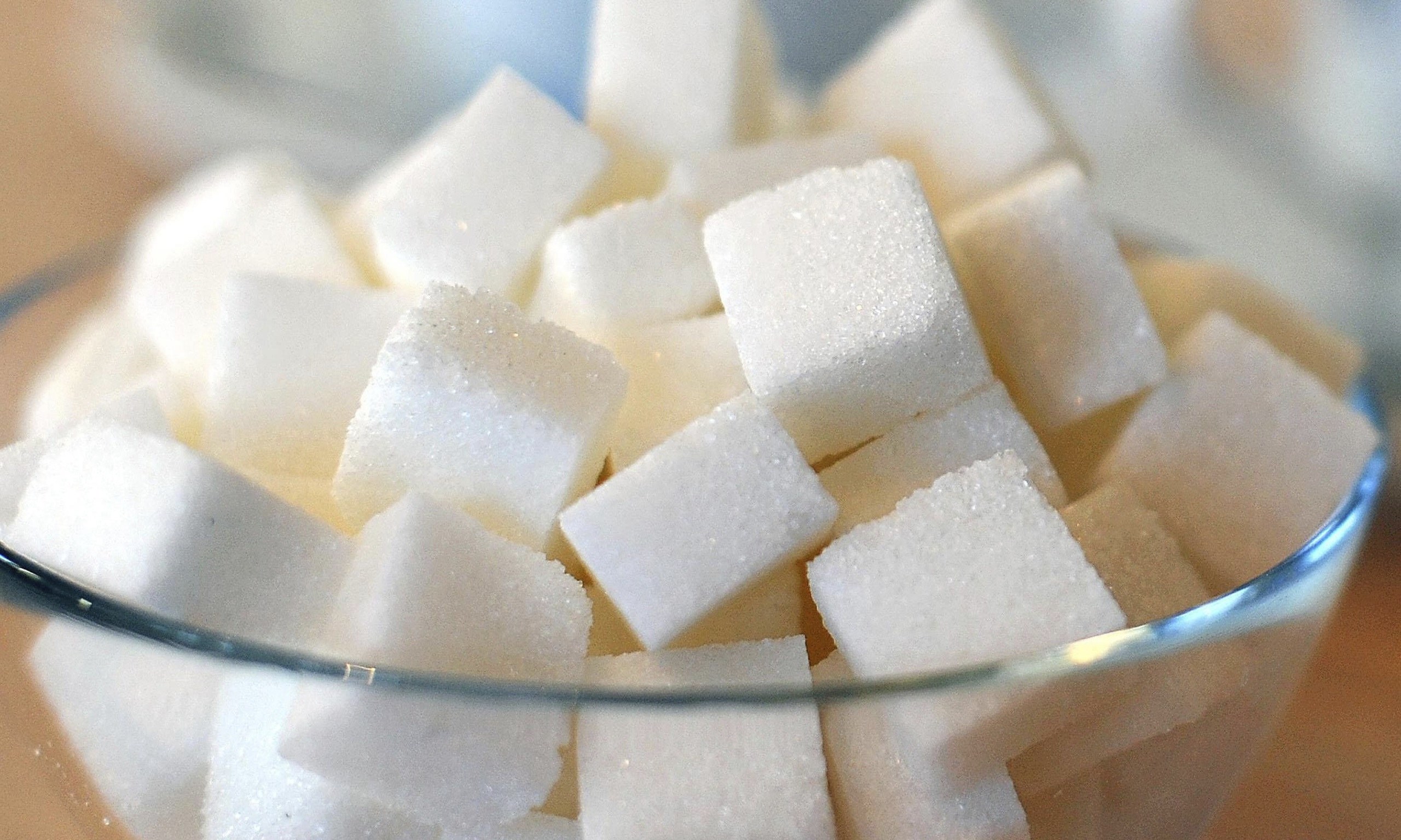 A glass bowl filled with white cubes of sugar.